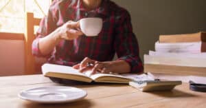 man reading about personal finance books with a cup of coffee and calculator